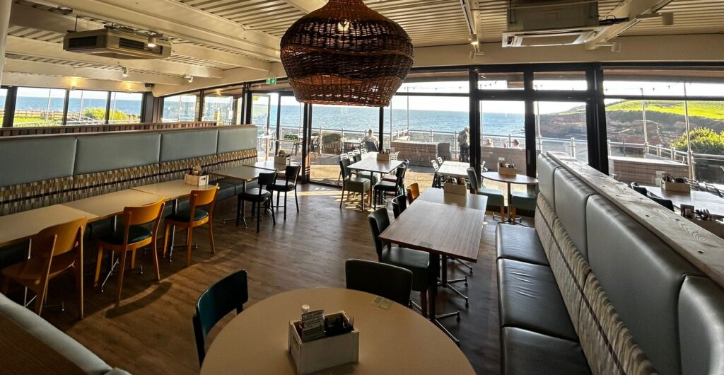 Pebbles restaurant interior with view of the sea and cliffs.