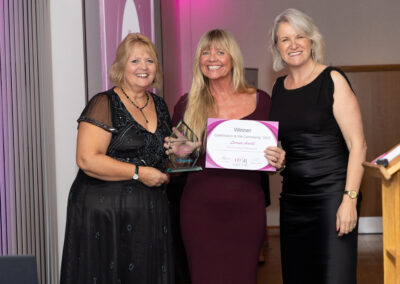 Sponsor, Jenny Paton (Newton Abbot Racecourse) presents Lorraine Arnold (Pier Point Bar & Restaurant) with the Contribution to the Community Award 2025 with host of the Devon Women in Business Awards, Louise Jenner.