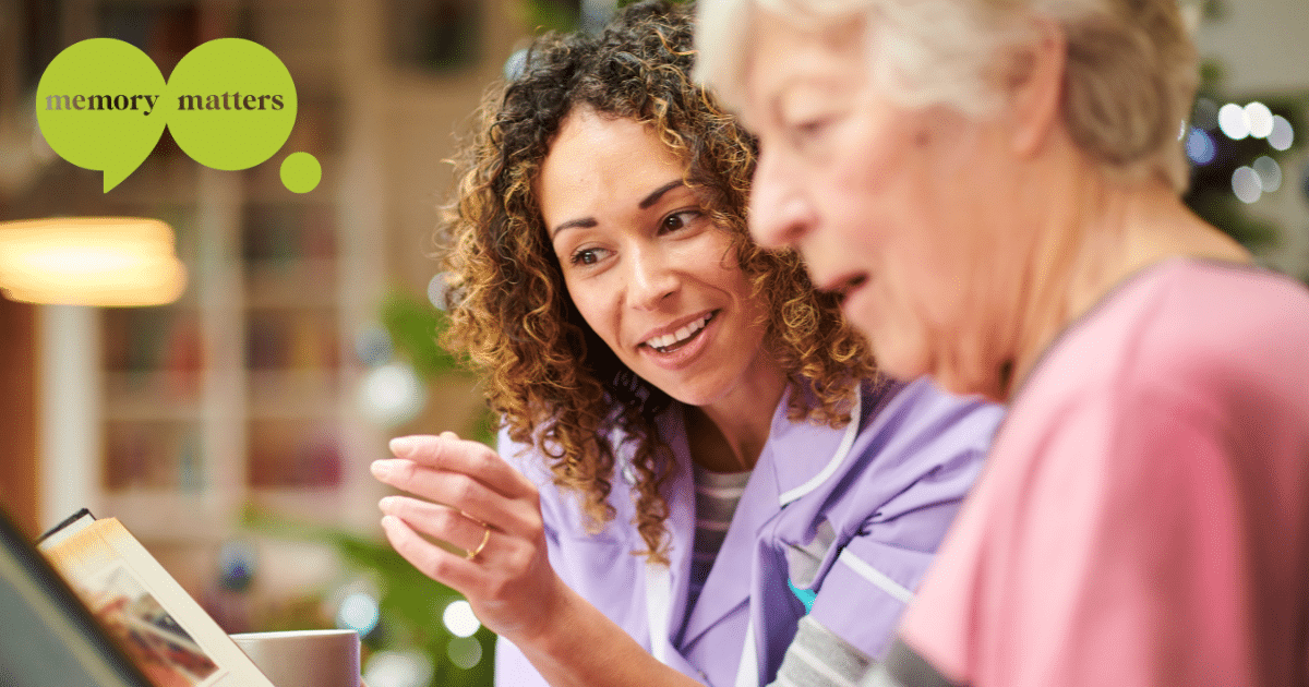 dementia-care-memory-matters Care worker supporting an older woman with dementia while looking at photos together.