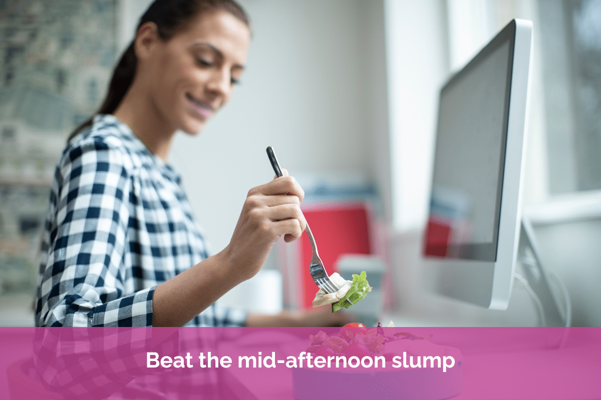 Professional woman enjoying a healthy lunch while working at her desk, highlighting the importance of regular meals for concentration, productivity and steady energy throughout the day.